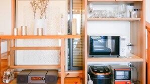A compact kitchen with a microwave, toaster, and coffee maker on the countertop. - Ocean View House (Atami)
