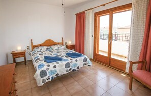 Relax in this serene bedroom with a comfortable bed, nightstand, and chair, plus a balcony offering a view of the outside.