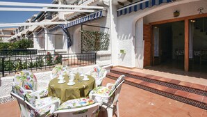 An outdoor patio with a table set for four, surrounded by white chairs with floral upholstery.