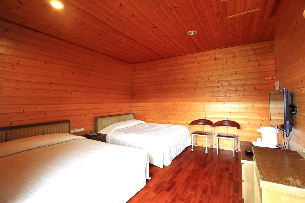 Une chambre aménagée dans un chalet en rondins, avec deux lits, un bureau en bois et une chaise.
