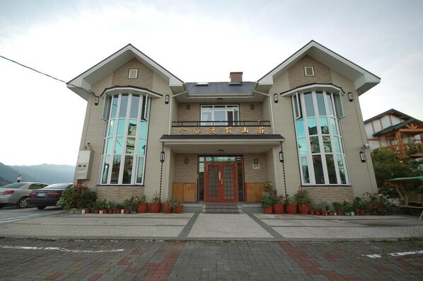 A two-story building with a central entrance, large windows on the upper floor, and potted plants in front. - Cingjing Farm Jenku Villa (Ren'ai)