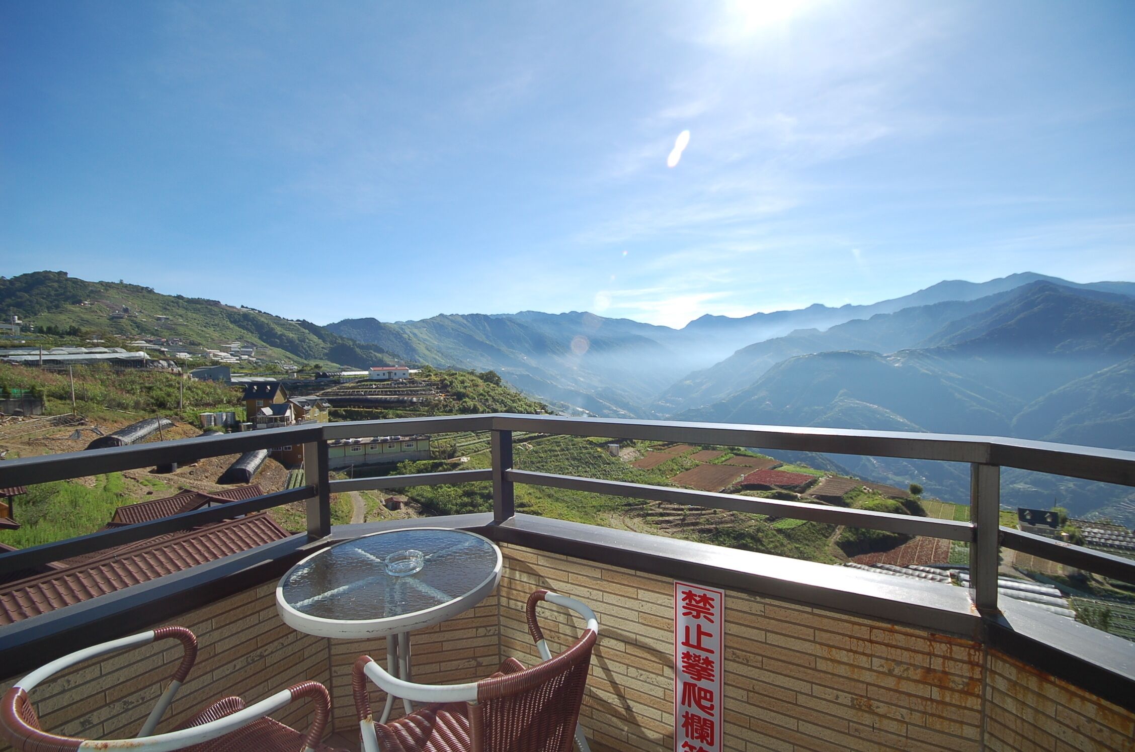Una terraza con mesa y sillas, con vistas a un paisaje montañoso con campos en terrazas.