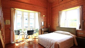 A wooden cabin room with a bed, two chairs, a window, and a radiator. - Cingjing Farm Jenku Villa (Ren'ai)