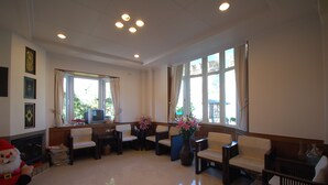 A spacious lobby with a fireplace, comfortable seating, and large windows offering a view of the outdoors. - Cingjing Farm Jenku Villa (Ren'ai)