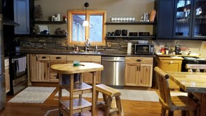 Une cuisine moderne avec un mur d’accent en pierre, des appareils en acier inoxydable, des armoires en bois et un îlot central doté de sièges.
