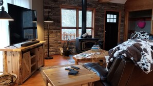 Un salon chaleureux avec un mur en pierre, une cheminée, un téléviseur et un confortable canapé en cuir.