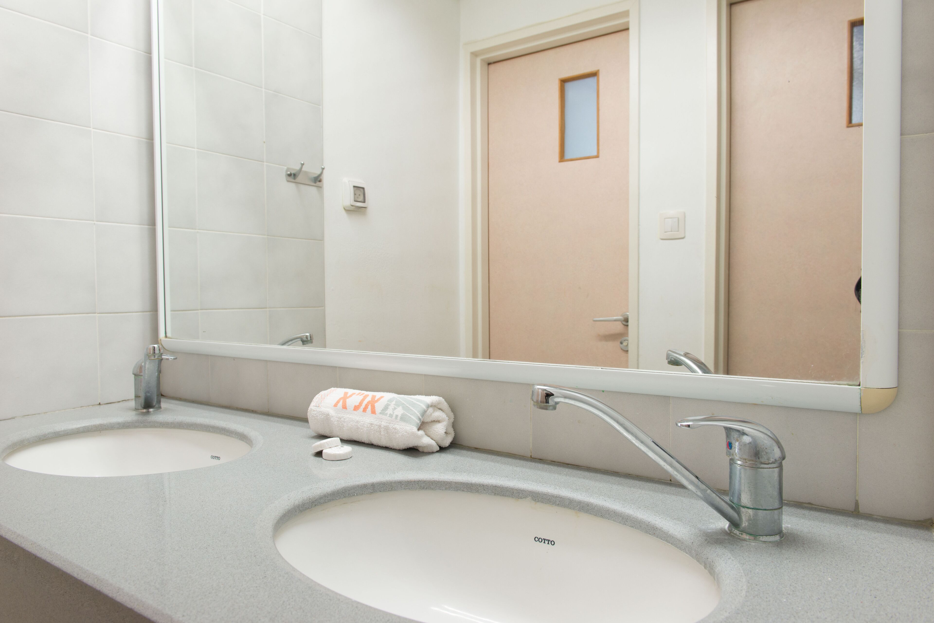 A bathroom with two sinks, a mirror, and a towel.