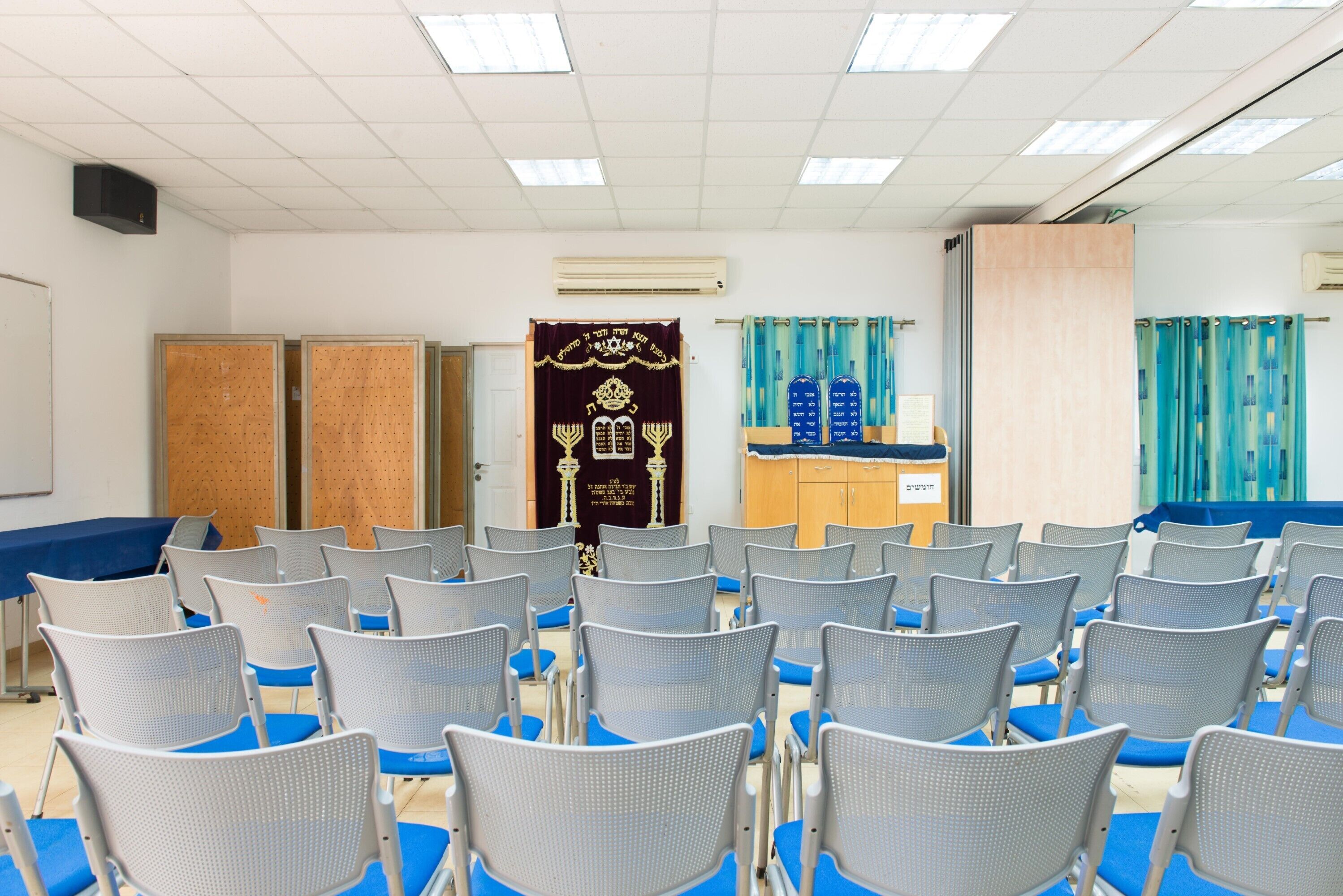 A conference room with rows of chairs, a podium, and a curtain backdrop.