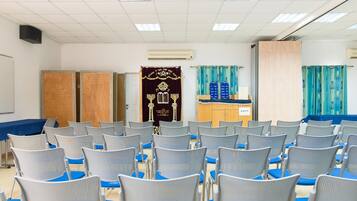 A conference room with rows of chairs, a podium, and a curtain backdrop.