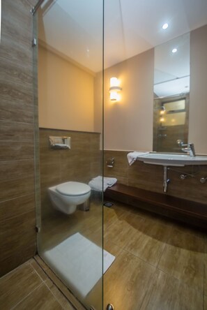 A modern bathroom with a glass shower enclosure, a white toilet, and a large mirror above the sink. - Taarifa Suites by Dunhill Serviced Apartments (Nairobi)
