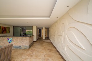 A modern interior with a reception desk, a patterned wall, and a tiled floor. - Taarifa Suites by Dunhill Serviced Apartments (Nairobi)