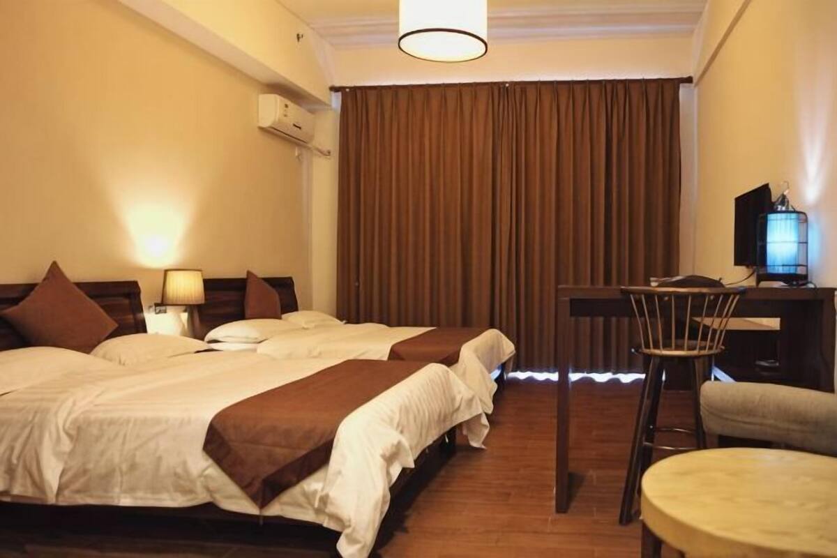 Een hotelkamer met twee bedden, een bureau, een stoel, een televisie en een lamp.