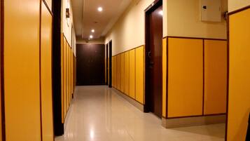 A corridor with lockers on both sides, a tiled floor, and doors at the end.