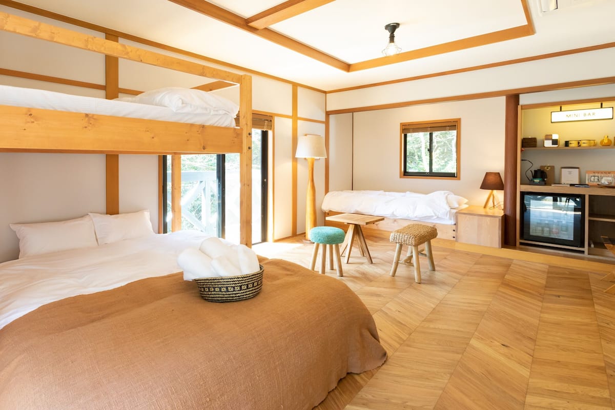 A bunk bed room with a desk, chair, and a mini bar.
