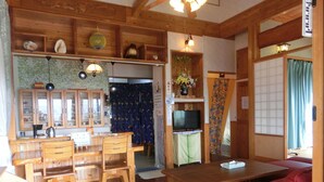 Ein traditioneller japanischer Raum mit Holzkunst, einem Tatami-Bodenbelag, einem Fernseher und einem roten Sofa.
