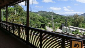 Ein hölzerner Balkon mit Blick auf eine üppige grüne Landschaft und Berge in der Ferne.