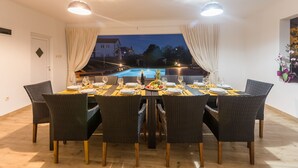 Un coin repas avec une table dressée pour six personnes, donnant sur une piscine.