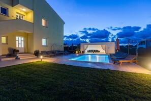 Un bâtiment moderne à deux étages doté d’une piscine, d’un espace extérieur aménagé et d’une pelouse bien entretenue.