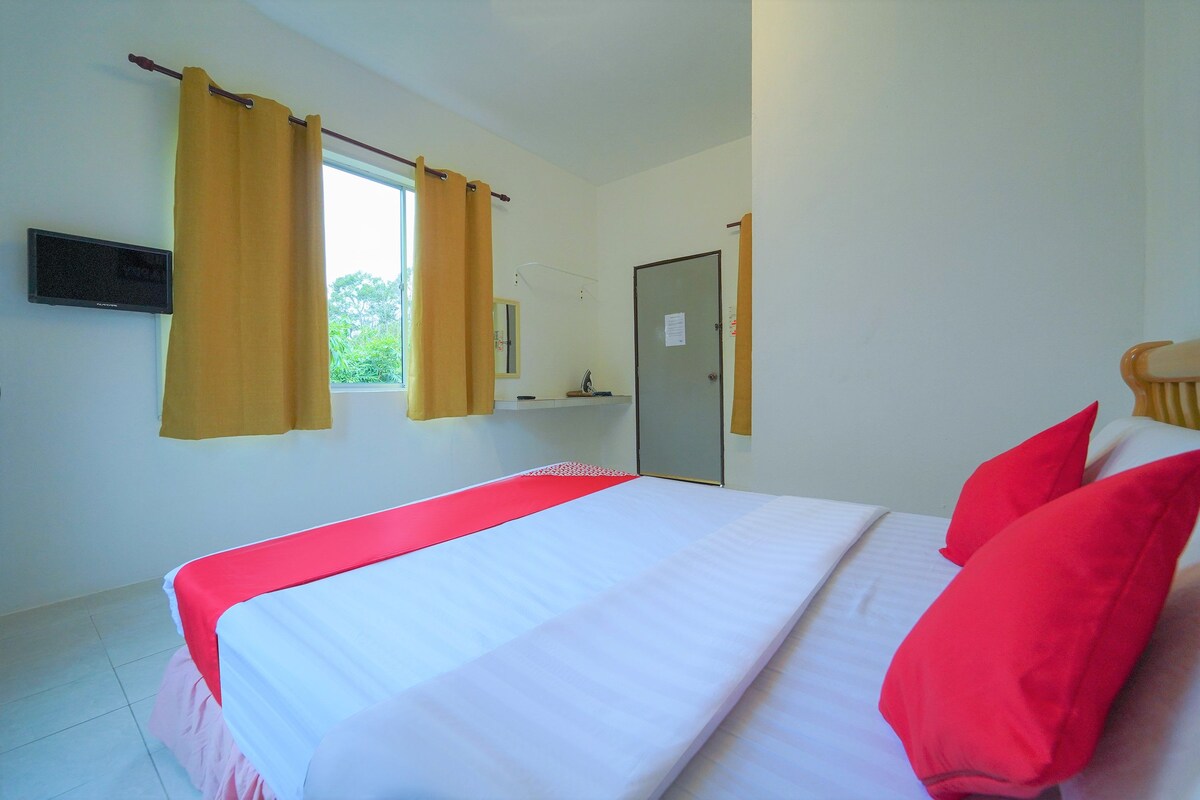 A hotel room with a bed, curtains, a door, and a window.