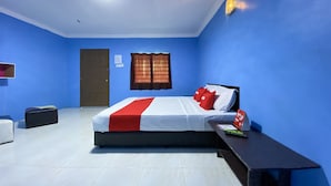 A hotel room with a bed, a nightstand, a desk, a chair, a wardrobe, and a window with curtains.