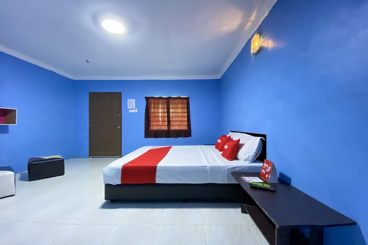 A hotel room with a bed, a nightstand, a desk, a chair, a wardrobe, and a window with curtains.