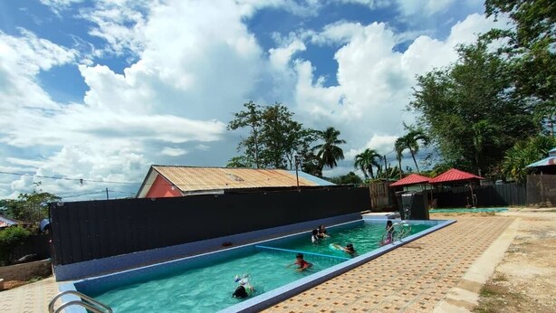 A swimming pool with clear blue water, surrounded by a tiled deck.