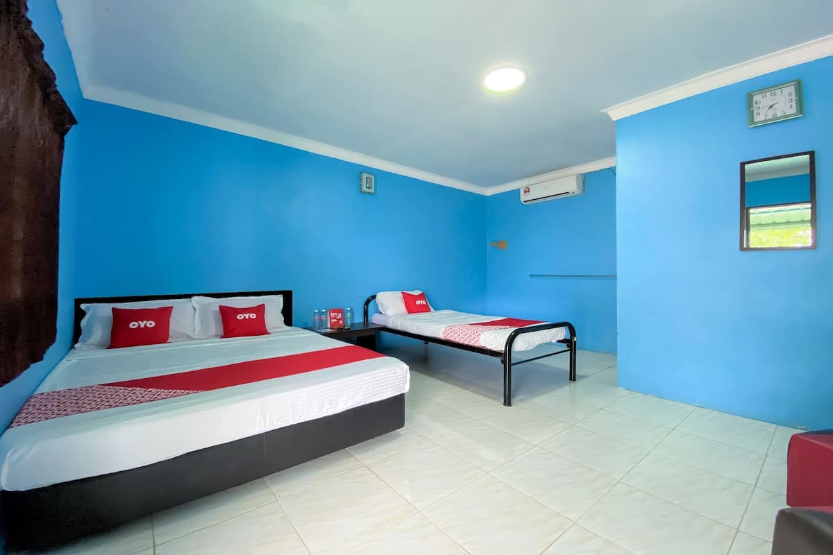 A hotel room with two beds, a red and white bedspread, and a red pillow with the word "OYO".