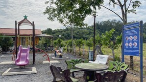 A playground with a slide, swings, and a table with chairs.