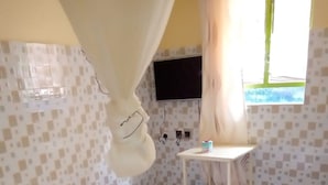 Una habitación con cama, una mesita, televisión y ventana.