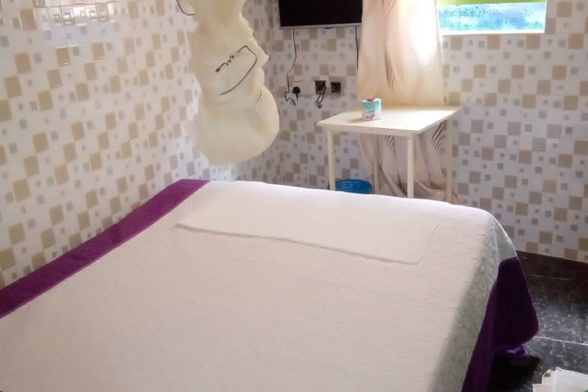 A room with a bed, a small table, a television, and a window.