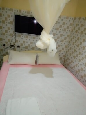 A hotel room with a bed, a television mounted on the wall, and a patterned wall.