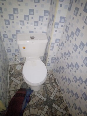 A small bathroom with a toilet, tiled floor, and patterned walls.