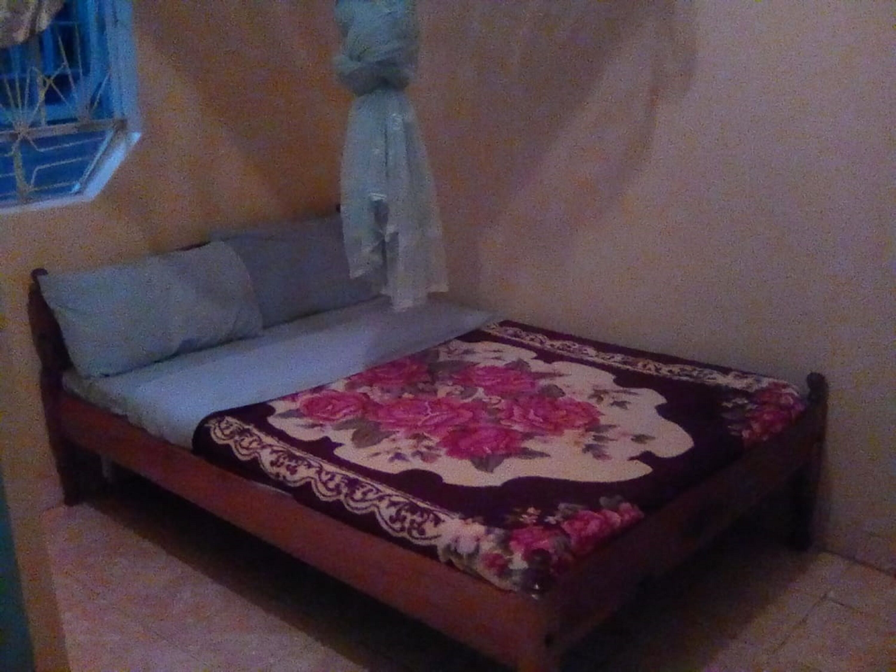 A single bed with a floral bedspread and a wooden frame.