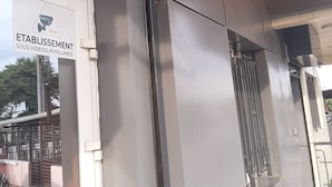 Entrada de un edificio con cámara de seguridad y un cartel que indica vigilancia las 24 horas.