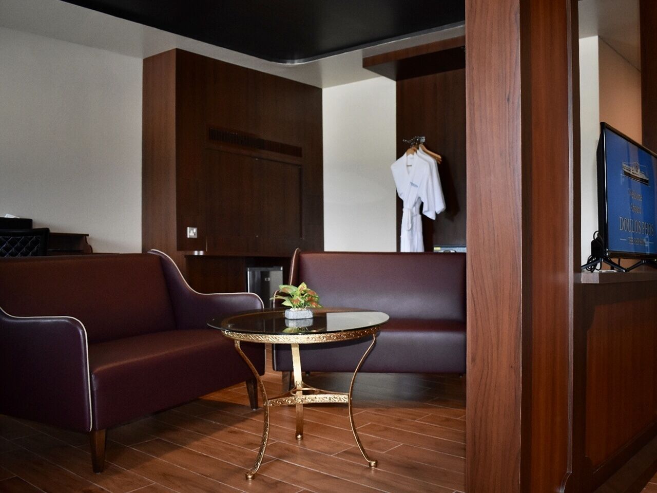 A room with a dark brown leather sofa, a round table with a gold base, and a wooden cabinet with a blue sign.