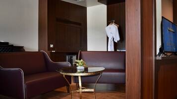 A room with a dark brown leather sofa, a round table with a gold base, and a wooden cabinet with a blue sign.