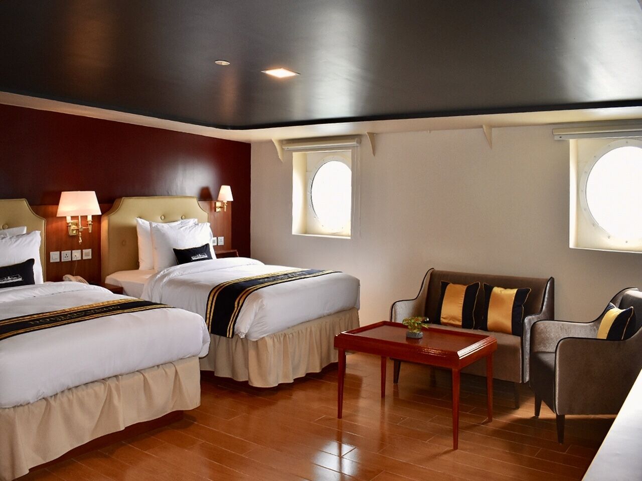 A hotel room with two beds, a sofa, a table, and a window.