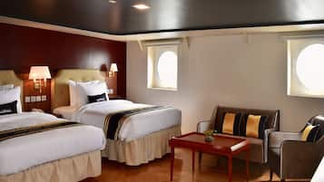 A hotel room with two beds, a sofa, a table, and a window.