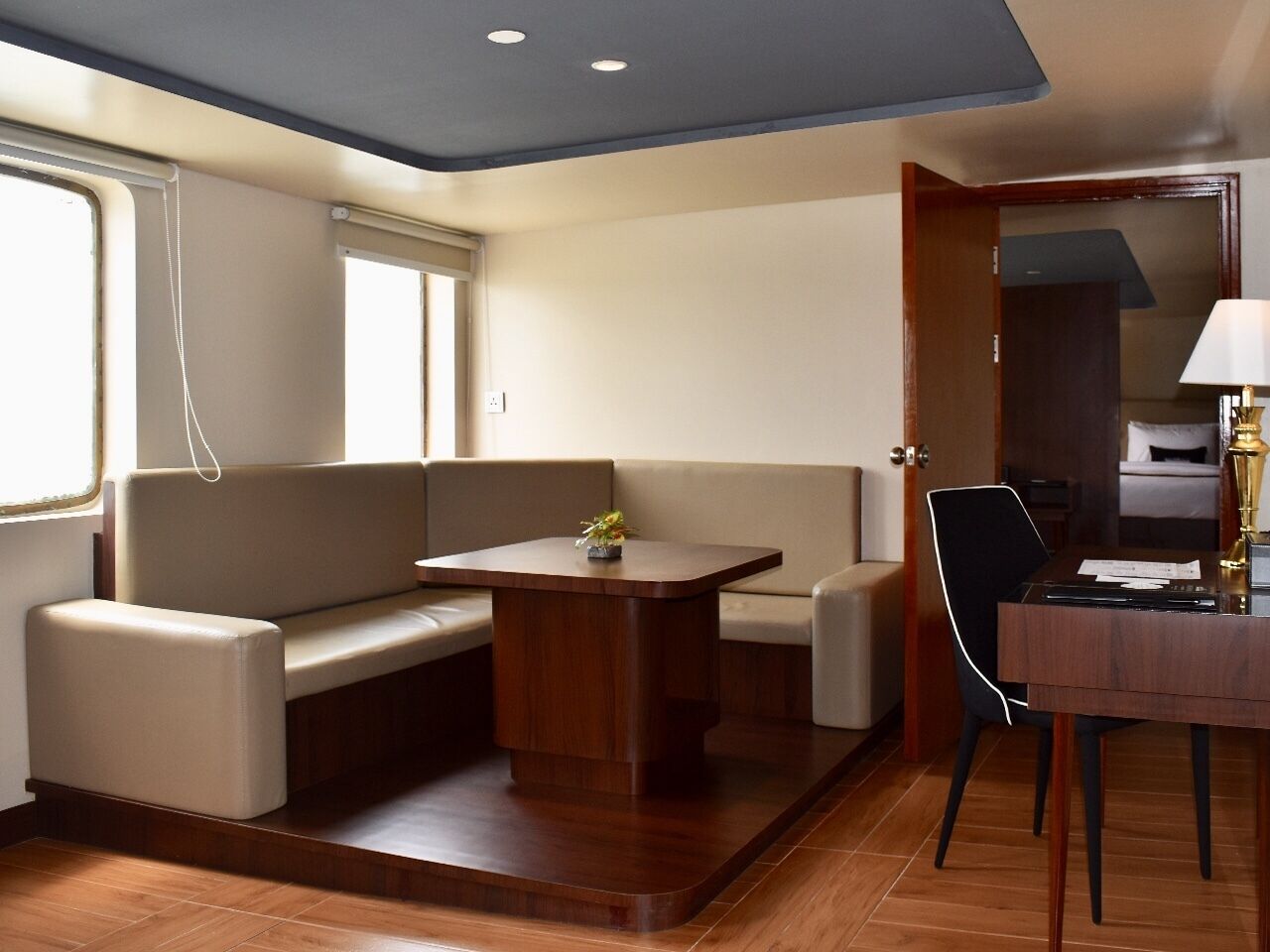 Quarto compacto com sofá, mesa pequena, escrivaninha e cadeira.