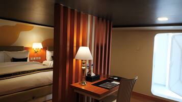 A hotel room with a bed, bedside lamps, a desk with a lamp, a chair, and a window.