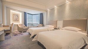 A hotel room with two beds, a desk, a chair, and a large window with a view. - Pantower International Hotel (Jiangmen)