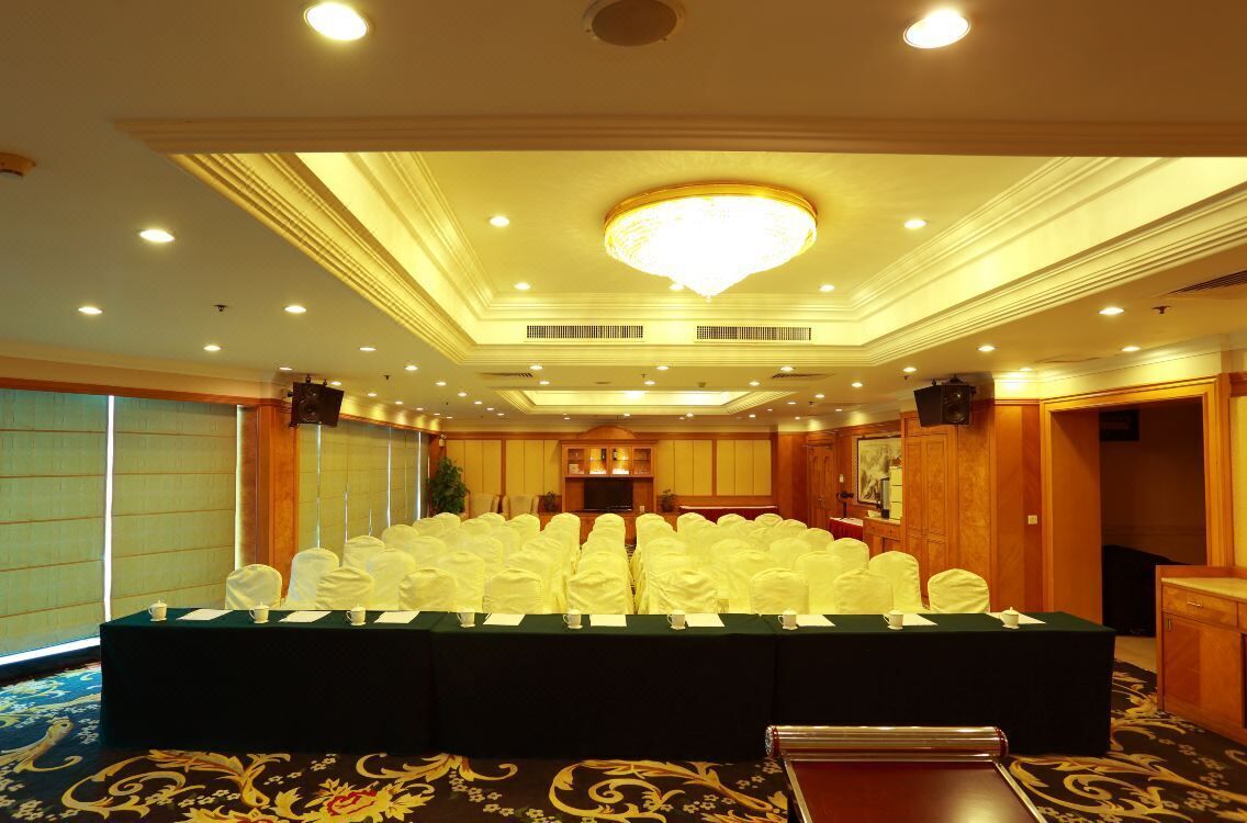 A conference room with a long table, white chairs, and a chandelier.