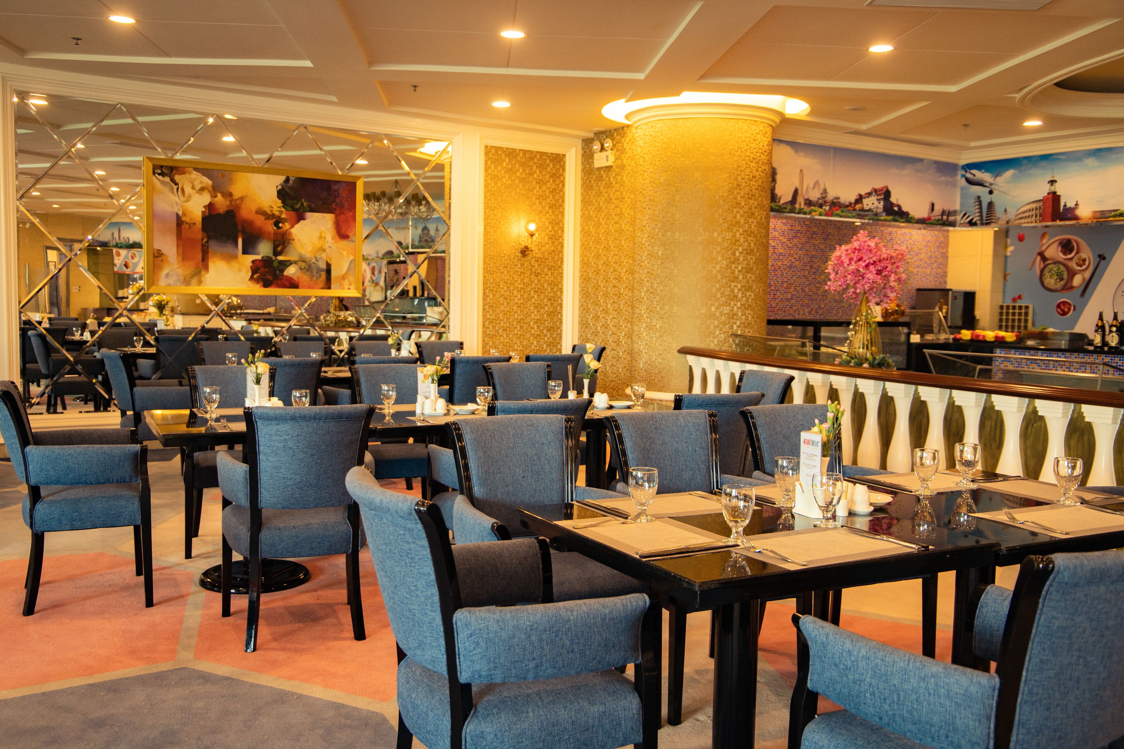 A restaurant with blue upholstered chairs, black tables, and a bar area with a decorative vase.