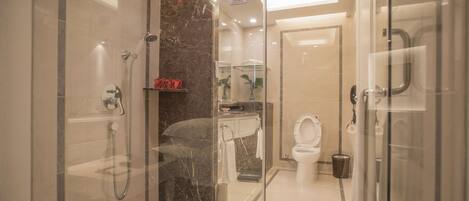 A modern bathroom with a glass-enclosed shower, a marble-tiled wall, a white toilet, and a sink with a mirror above it.