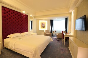 Una habitación de hotel con una cama grande, un escritorio, una silla y un televisor.