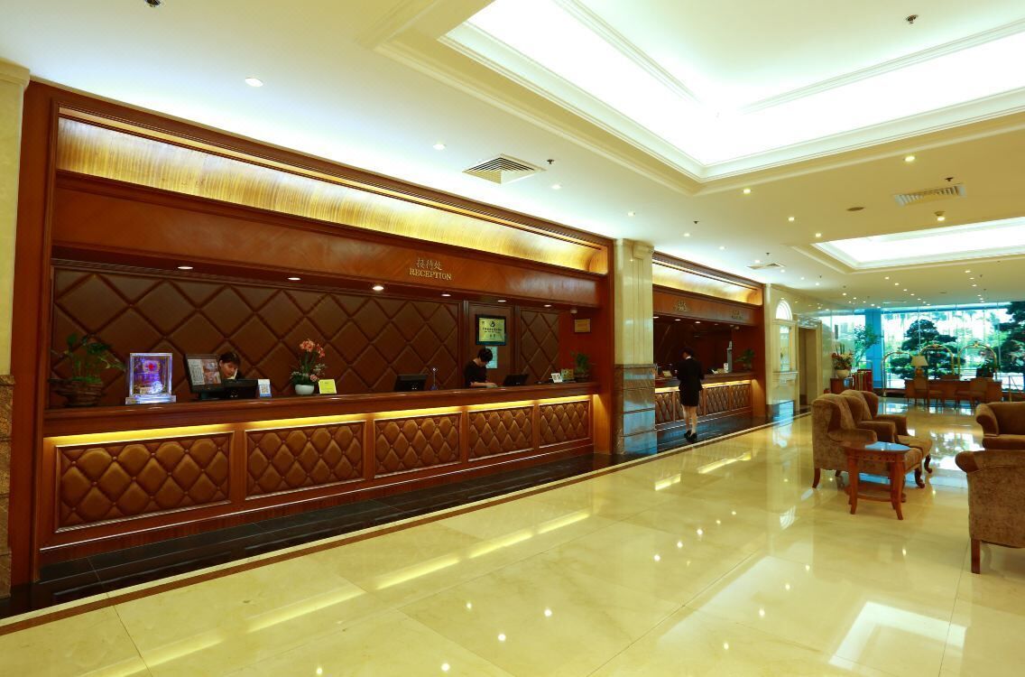 A hotel reception area with a reception desk, seating area, and a view of the outdoors.