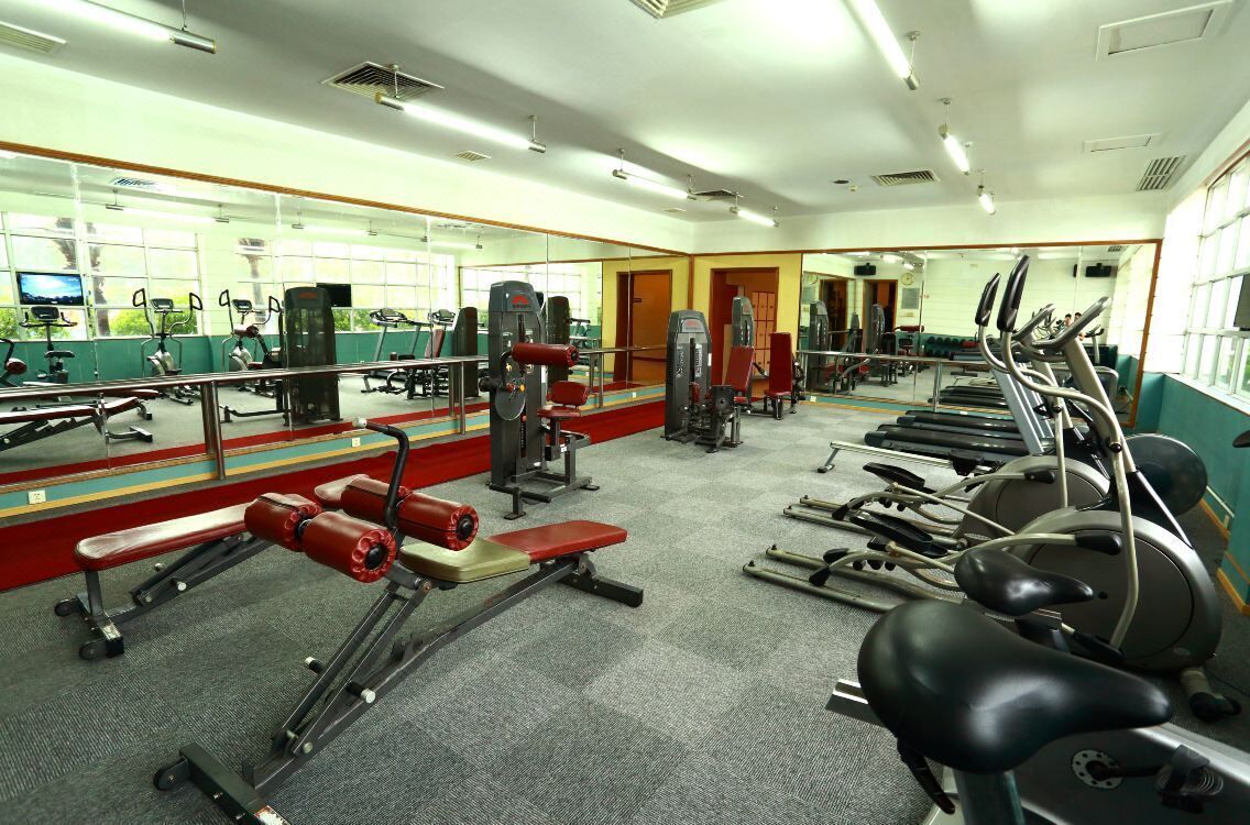 A gym with various exercise equipment, mirrors, and a carpeted floor.
