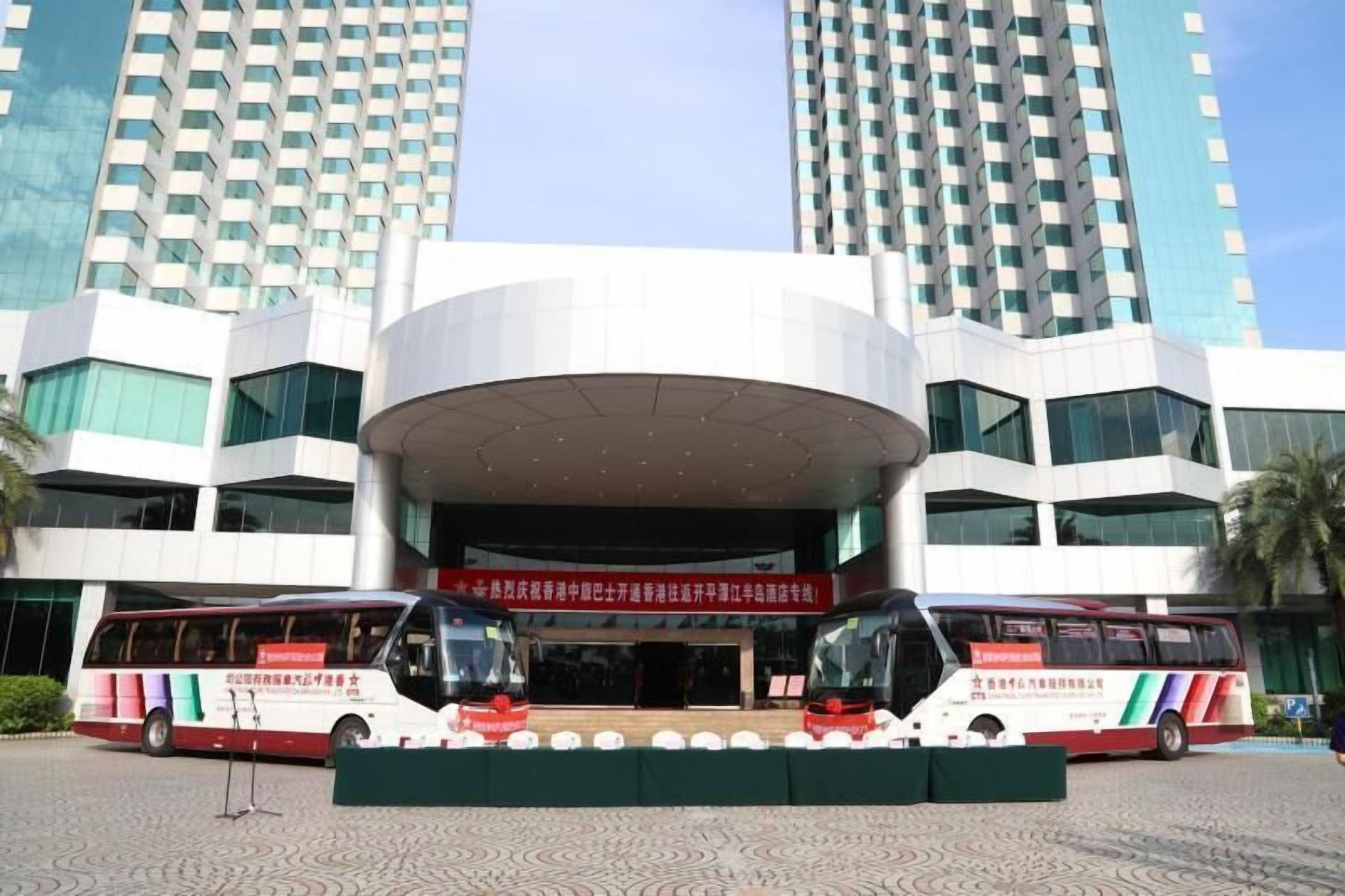A modern building with a large entrance and two buses parked in front.