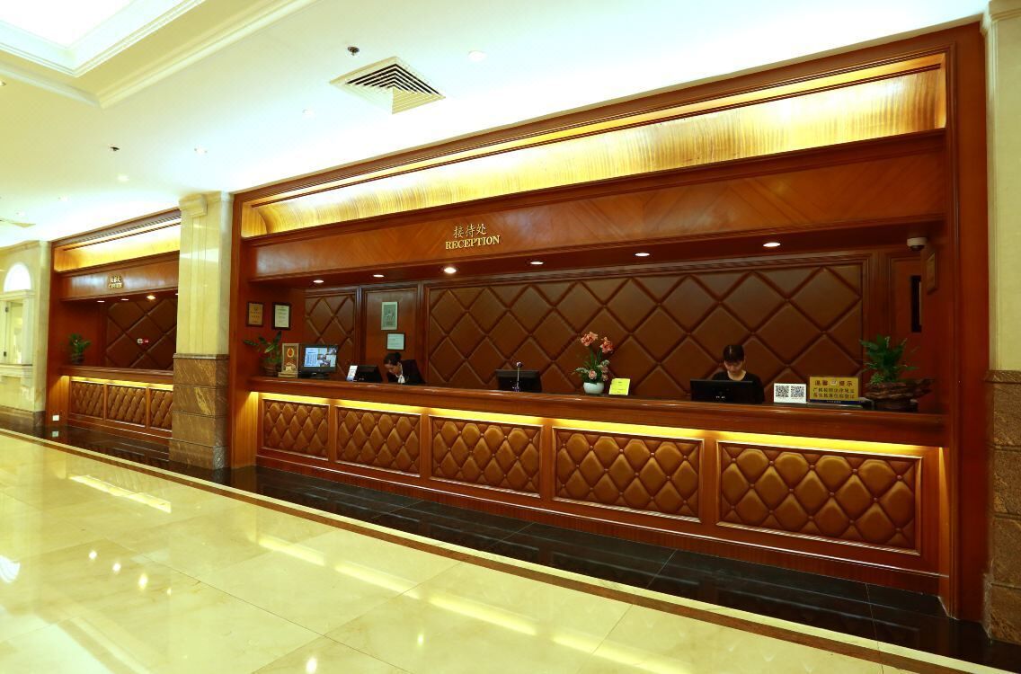 A reception area with a wooden reception desk, a sign indicating 'RECEPTION', and a plant on the counter.