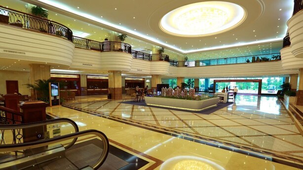A spacious lobby with multiple floors, a central atrium, and a large chandelier. - Pantower International Hotel (Jiangmen)